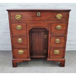 An 18th century mahogany kneehole writing desk with nine drawers about the cupboard,