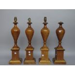 A set of four fruitwood table lamps each of tapering urn form raised on a square plinth, 46cm high,