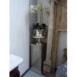 A pair of modern nickel plated metal urns each containing faux orchids,