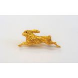A 14ct gold brooch, designed as a running hare, with cabochon ruby set .