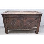 A 17th century carved oak coffer with twin panel lid and front on stile feet,