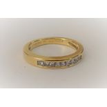 A gold and diamond ring, mounted with a row of nine princess cut diamonds, detailed 0.