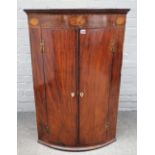 A mid-18th century inlaid mahogany hanging bowfront two door corner cabinet, 72cm wide x 109cm high.