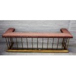 A modern brass club fender with upholstered seat over pillared supports and a stepped kerb,