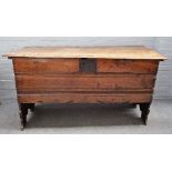 A large 17th century elm coffer, with channelled lid and front, on shaped slab end supports,