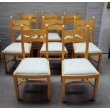 A set of eight beech framed wavy back dining chairs, on block supports, united by sloped stretcher,