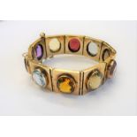 A gold and varicoloured gemstone set bracelet, formed as a row of rectangular links,