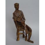 A patinated bronze figure, of abstract form, modelled seated in a chair,