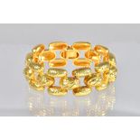 A gold bracelet, in a three row domed link design, with a partly martele finish, on a snap clasp,