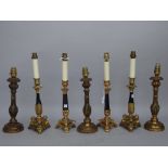 A pair of modern gilt metal table lamps of 18th century candlestick style, raised on a triform base,