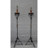 A pair of 17th century style wrought iron standard lamps each with castellated circular rim,