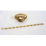 A gold oval hinged bangle, the front in an entwined design,