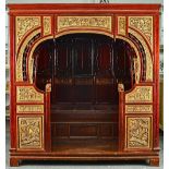 A late 19th century Chinese red lacquer parcel gilt opium bed with rounded entrance and panel