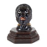 An early 20th century hardwood carved figural inkwell, pre-1918, modelled as a Nubian man,