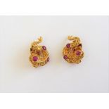 A pair of gold and cabochon ruby earclips, each in a cast serpentine design, having a rustic finish,