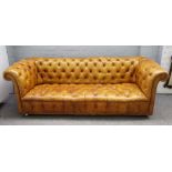 A 20th century studded tan leather upholstered button back Chesterfield sofa on bun feet,