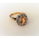 An 18ct gold, topaz and diamond oval cluster ring, claw set with the oval topaz at the centre,