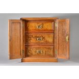 A Victorian oak table top cabinet, the pair of panel doors enclosing three figured walnut drawers,
