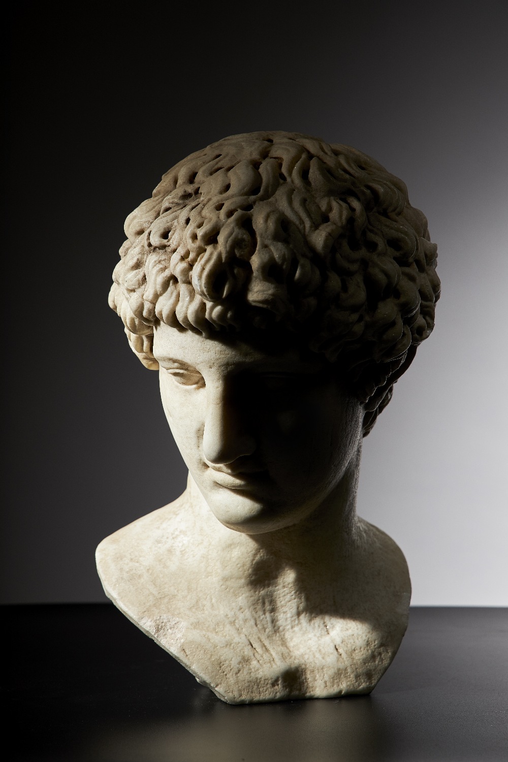 After the Antique; a carved white marble portrait bust of a man, drill carved hair,