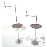 A pair of modern chromed adjustable standard lamps with central circular tier over a weighted