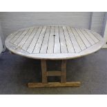 A large teak circular slatted garden table, 180cm diameter, together with six chairs,
