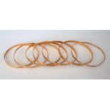 Seven 9ct gold circular bangles, in a variety of designs, with engraved decoration,