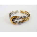 A two colour gold bangle, in an entwined ropetwist design, the front with a knot motif,