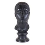 A late 19th/early 20th century black painted plaster bust of a Nubian man, on turned socle,