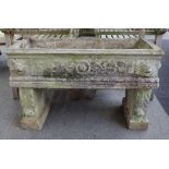 A pair of reconstituted stone rectangular planters with lion mask decoration on scroll supports,