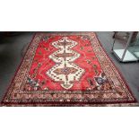 A Persian rug, red ground with triple pole medallion in ivory, boteh decoration,