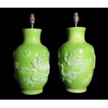 A pair of 20th century Chinese green ceramic table lamps moulded with dragons with character marks