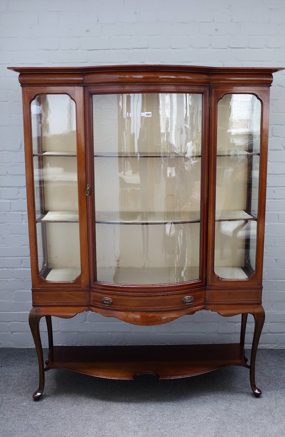 An Edwardian inlaid mahogany bowfront display cabinet with single door over drawer on cabriole