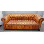 A 20th century studded tan leather upholstered button back Chesterfield sofa on bun feet,