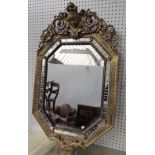 A 19th century Italian mirror with face mask crest over compressed octagonal frame with segmented