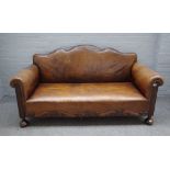 A 20th century brown leather upholstered hump back sofa with carved lower frieze,