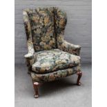 A George II style wingback armchair on walnut cabriole supports 91cm wide x 110cm high.