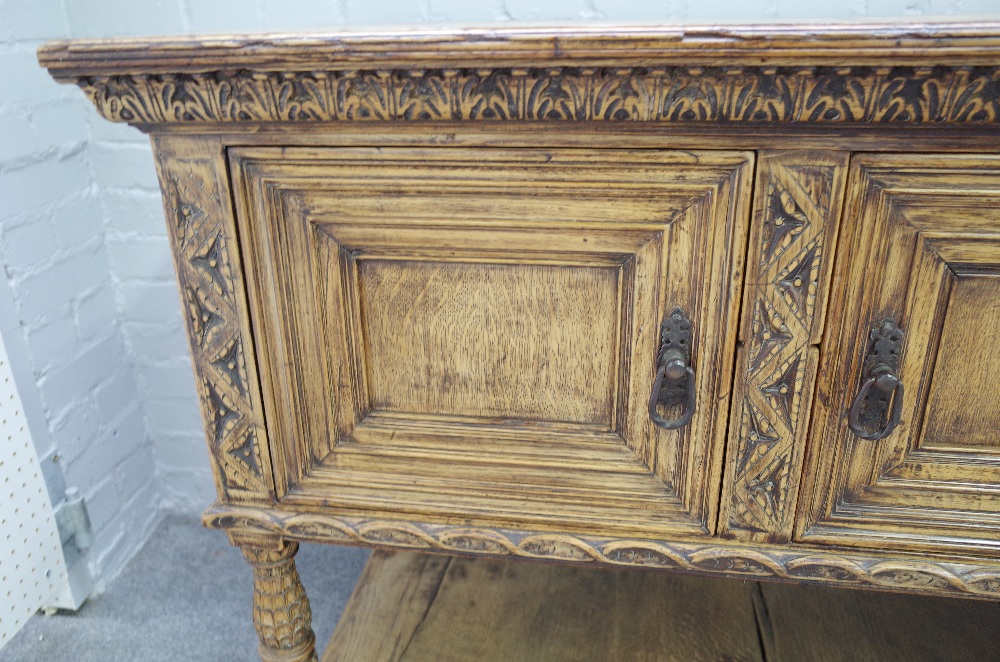 A 17th century style carved oak dresser base, with three recessed panel doors, on turned supports, - Image 2 of 5