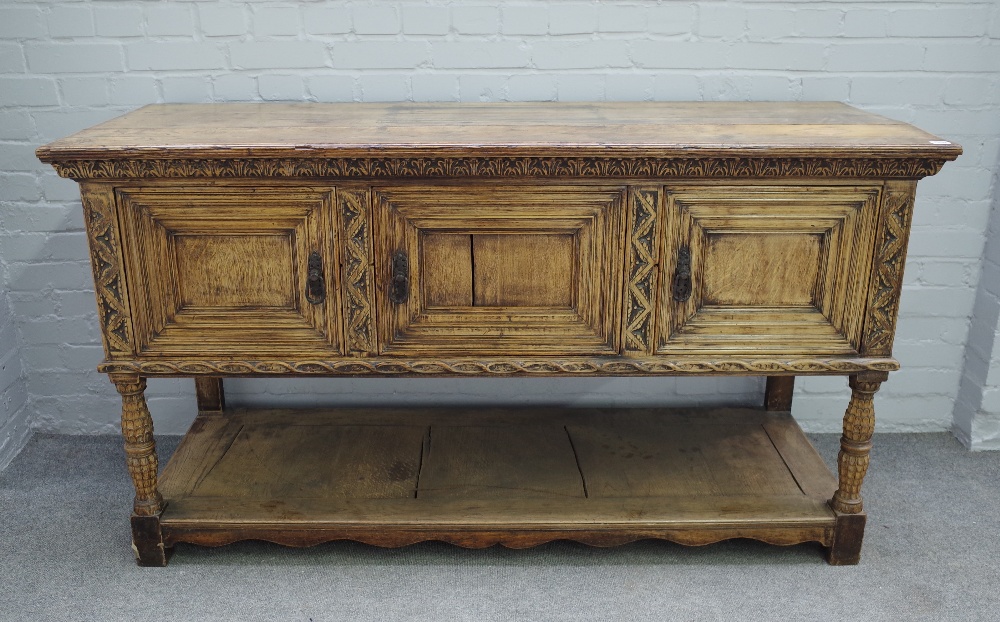 A 17th century style carved oak dresser base, with three recessed panel doors, on turned supports,