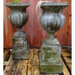 A pair of reconstituted stone jardiniere's with fluted bodies on stepped square pedestals,