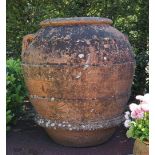 A large terracotta oil jar of bulbous tapering form, with banded body, 107cms high.
