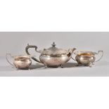 A silver three piece tea set, comprising; a teapot with black fittings,