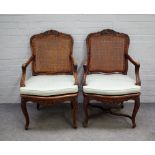 A pair of late 18th century French walnut cane back open armchairs with serpentine seat on cabriole