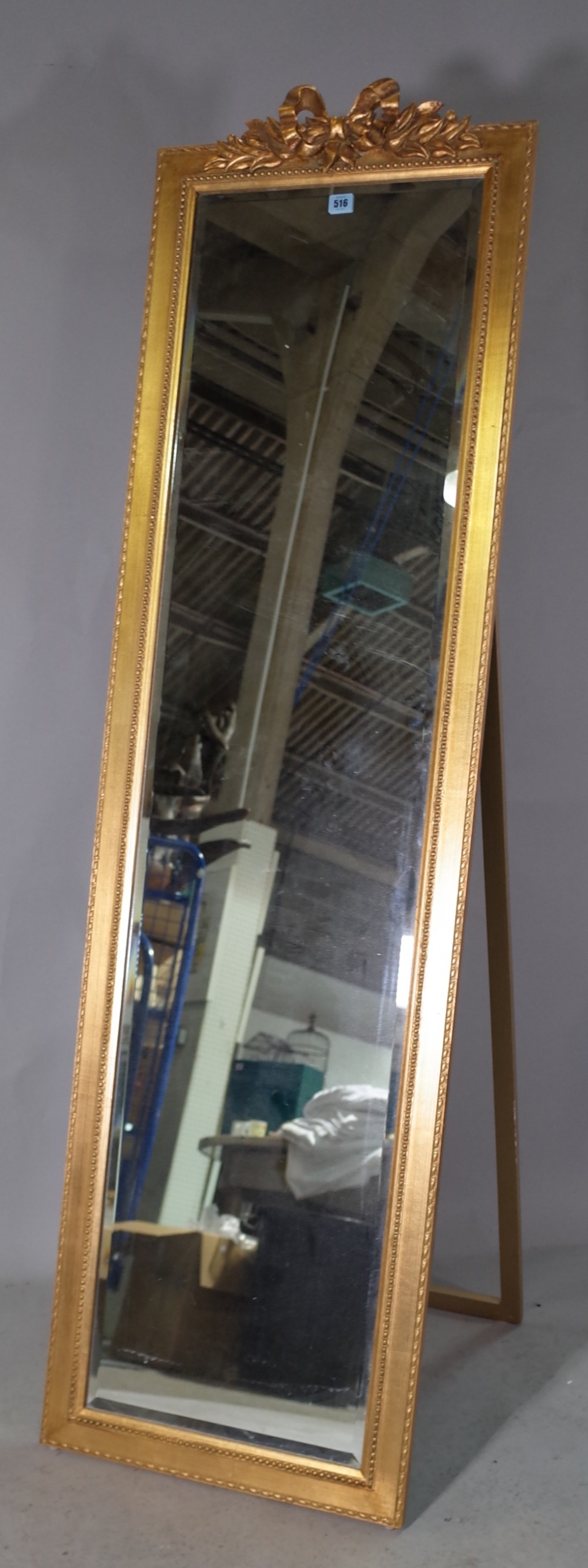 A 20th century gold painted floor standing dressing mirror with ribbon tied crest,