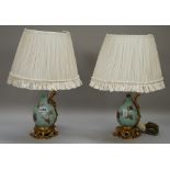A pair of Chinese porcelain and ormolu mounted ewer table lamps, with pleated cream shades,