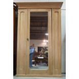 An early 20th century pine double wardrobe with mirrored central door on plinth base,