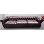 A large brown leather upholstered Chesterfield sofa, on turned supports, 300cm wide x 69cm high.