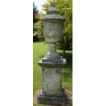 A pair of reconstituted stone urns, probably 20th century, on earlier square stone plinths,