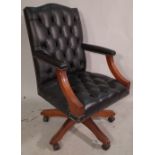A 20th century swivel office open armchair, with faux black leather button back upholstery.