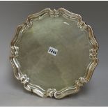 A silver salver, of circular shaped form, having a pie-crust rim, raised on three scrolling feet,