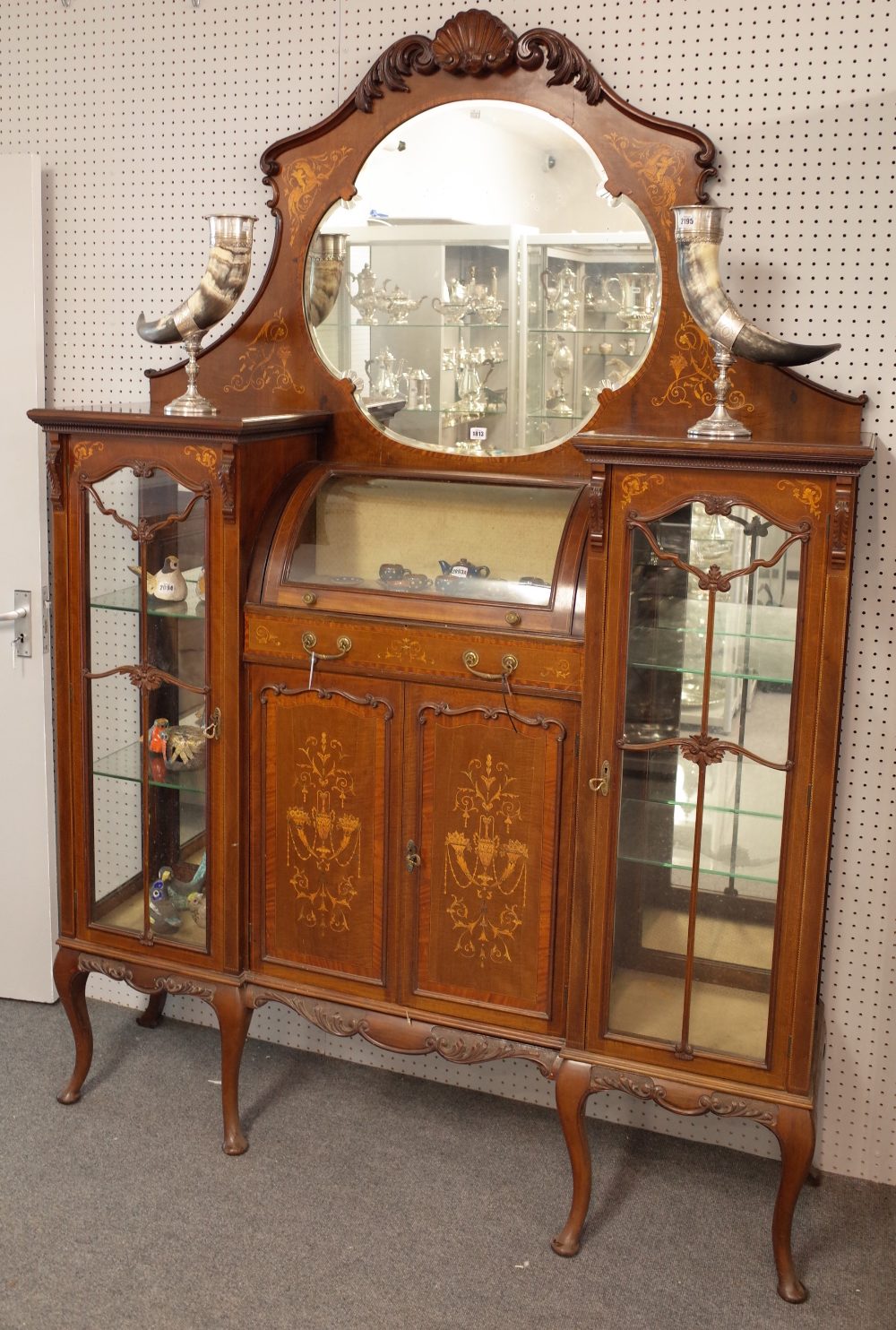 An Edwardian inlaid mahogany mirrored back display cabinet with bowed central compartment over